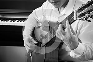 Young Asian man play guitar. Classical music instrument. Art and music portrait background. Black and white color tone.