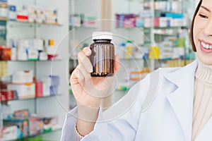 Closeup young asian pharmacist pill bottle mockup at qualified pharmacy