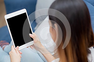 Closeup young asian woman sitting and using mockup of tablet computer with display blank screen on sofa at home.