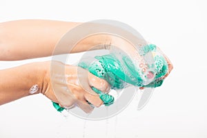 Female squeeze wring out wet fabric cloth with detergent have soapy bubble in water photo