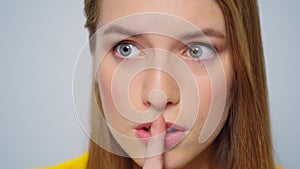 Closeup young attractive woman showing silence sign on grey background.