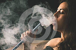 Young, beautiful girl smoke a hookah at club