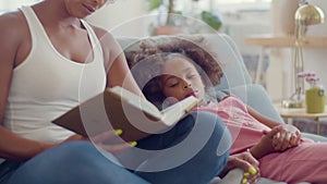 Closeup of young Black woman reading fairy tales to her child.