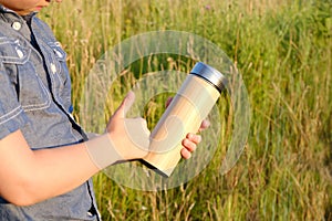 closeup young boy, child 8-10 years old quenches thirst from wooden thermos, concept body hydration, fitness equipment, active