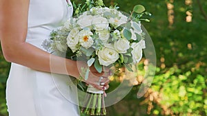 Closeup young bride in fitted wedding white dress holding a beautiful bridal bouquet