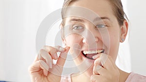 Closeup of young brunette woman taking care of her teeth and using dental floss. Concept of teeth health, self checking mouth and