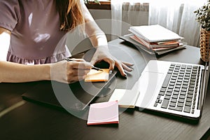 Closeup of young businesswoman working at modern office making notes