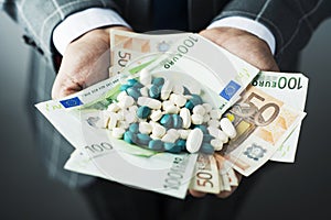 Businessman with a pile of pills and euro bills photo