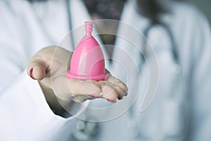Doctor woman showing a pink menstrual cup photo