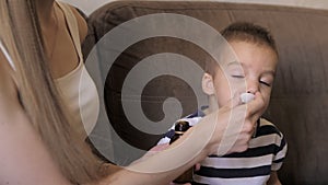 Closeup of young caucasian mother is giving medicine in the special plastic spoon to the little 2 years cute boy. Kid