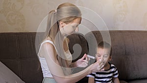 Closeup of young caucasian mother is giving medicine in the special plastic spoon to the little 2 years cute boy. Kid