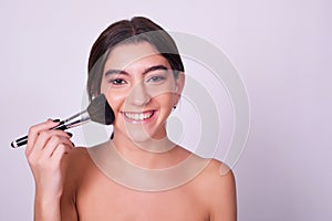 Closeup of young caucasian woman applying makeup