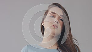 Closeup of young caucasian woman with long hair moved by wind slowly blye eyed model portrait,