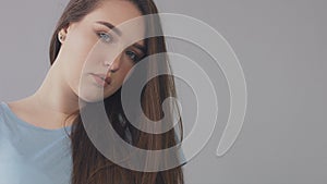 Closeup of young caucasian woman with long hair moved by wind slowly blye eyed model portrait,