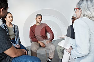 Closeup of a young diverse support group during a meeting with a professional female therapist. Group of employees