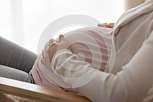 Closeup of young female expectant mother touch big baby bump