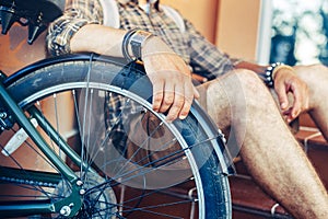 Closeup young guy hand lies on a bicycle wheel