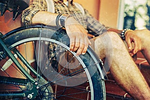 Closeup young guy hand lies on a bicycle wheel