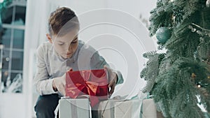 Closeup young guy taking gift near christmas tree in luxury house.