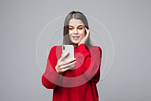 Closeup of young happy woman wearing in red sweater with mobile phone, over white background