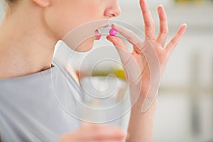 Closeup on young housewife eating pill