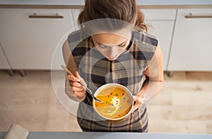 Closeup on young housewife eating pumpkin soup