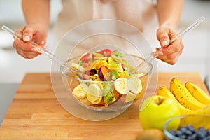 Closeup on young housewife making fruit salad