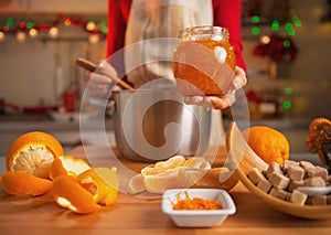 Closeup on young housewife making orange jam in kitchen