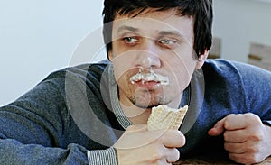 Closeup of young lousy man eats ice cream.