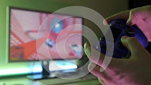 Closeup of young man hands playing video games on gaming console in front of TV widescreen