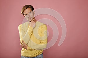 Closeup of young man looking up thinking on pink background