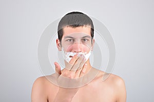 Closeup of young man preparing to shave, he puts foam on his c