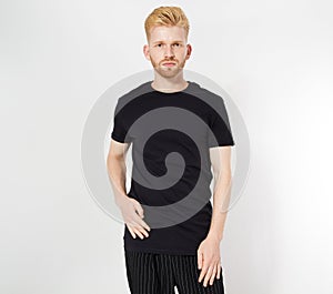 Closeup of young man`s body in empty black t-shirt on white gray wall background. T shirt Mock up