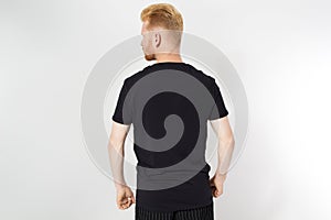 Closeup of young man`s body in empty black t-shirt on white gray wall background. T shirt Mock up