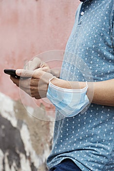 Man using his smartphone wearing a mask in his arm