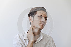 Closeup of a young man suffering from neck ache isolated on white background