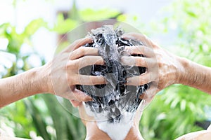 Closeup young man washing hair with shampoo outdoor, health care concept, selective focus