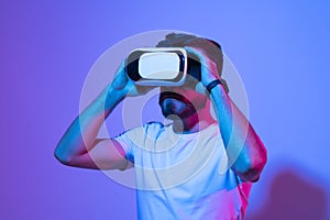 Closeup of young man wearing virtual reality goggles in modern studio. Smartphone using with VR headset.
