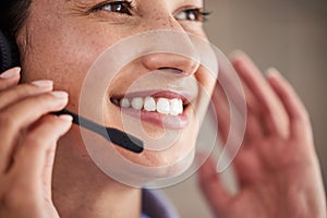 Closeup of young mixed race female call center agent wearing headset and talking to clients customers. Face of smiling