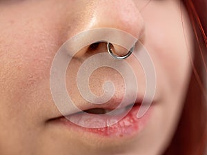 Closeup of a young teen girl\'s visage with piercing hanging from her nose