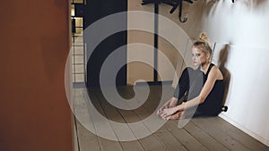 Closeup of young teenage girl dancer crying after loss perfomance sits on floor in hall indoors