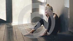 Closeup of young teenage girl dancer crying after loss perfomance sits on floor in hall indoors