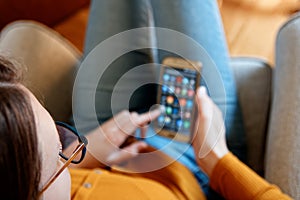 Closeup of young woman from above using smart phone at home yellow orange colors