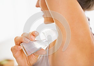 Closeup on young woman applying deodorant on underarm photo