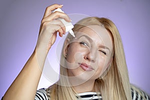 Closeup of young woman applying eye drops