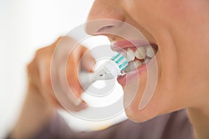 Closeup on young woman brushing teeth