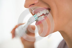 Closeup on young woman brushing teeth