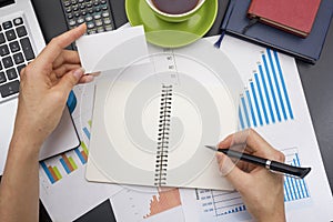 Closeup of a young woman checking accounts. Office desk table with supplies top view