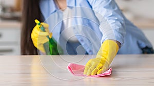 Closeup of young woman cleaning table with cloth