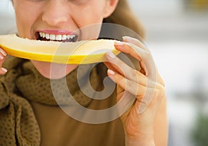 Closeup on young woman eating melon in kitchen